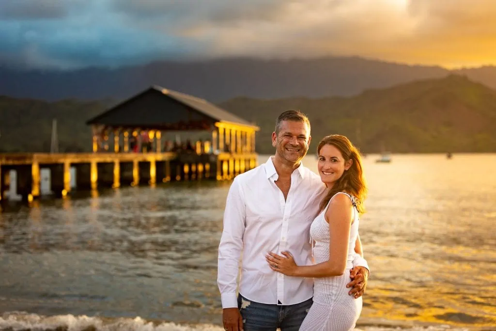 An elopement couple smiles at the camera at Hanalei bay, Kauai.