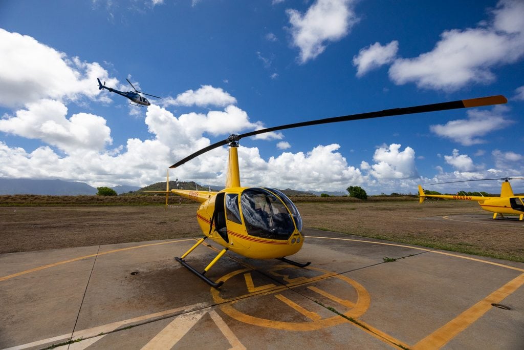A yellow helicopter sits at the airport in Lihue, Kauai, ready for a helicopter tour.