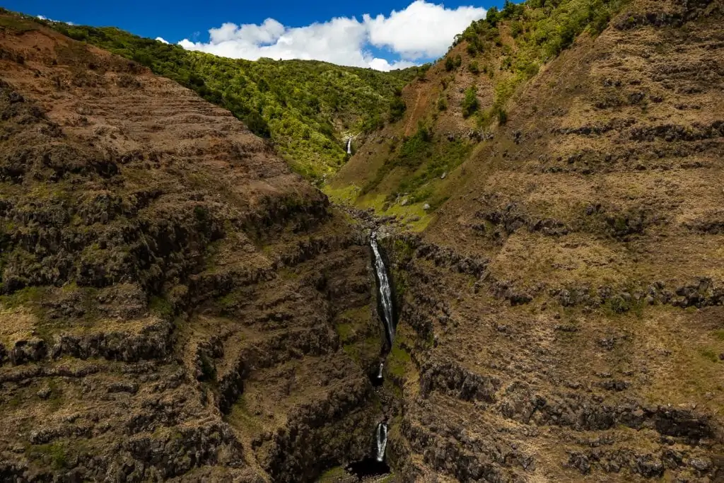 A waterfall in Waimea Canyon photographed from above by helicopter.