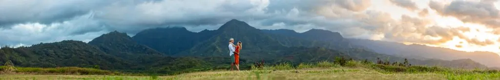 A big panorama of a couple in the mountains of Kauai at sunset.