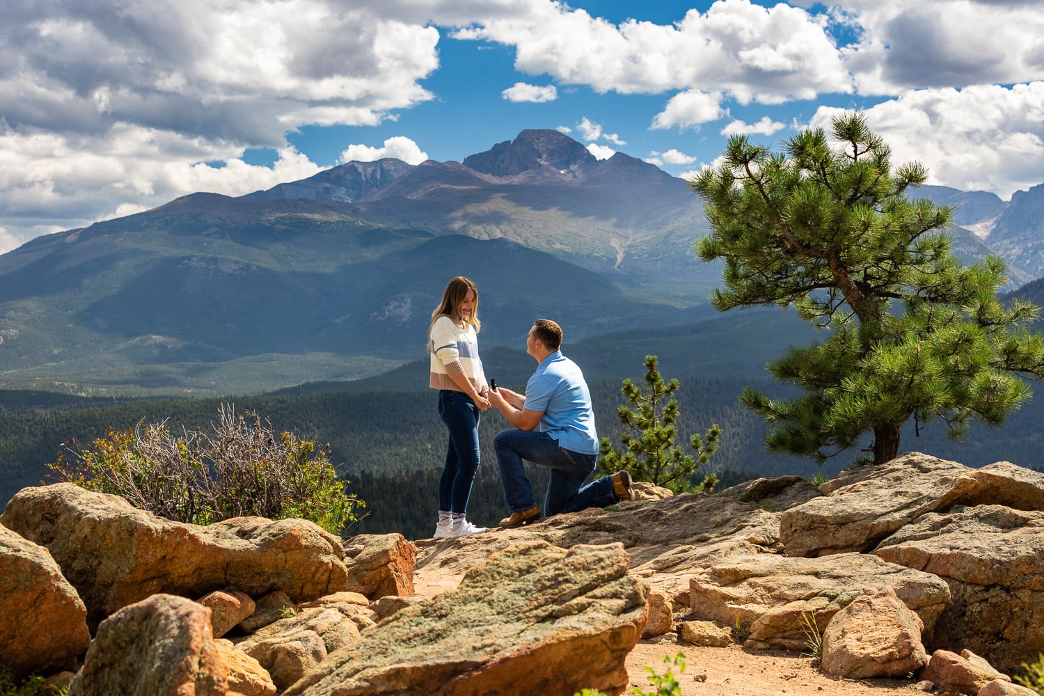 a man gets down on one knee in Rocky Mountain National Park to propose to his girlfriend.