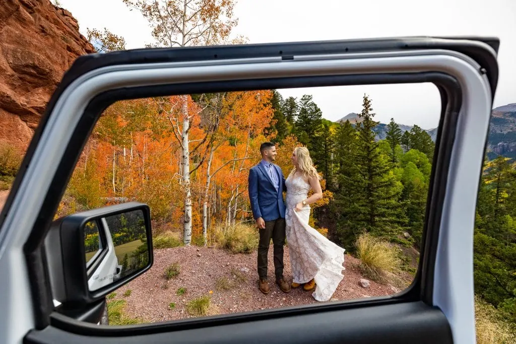 An elopement couple on imogene pass road in telluride with red fall aspens.