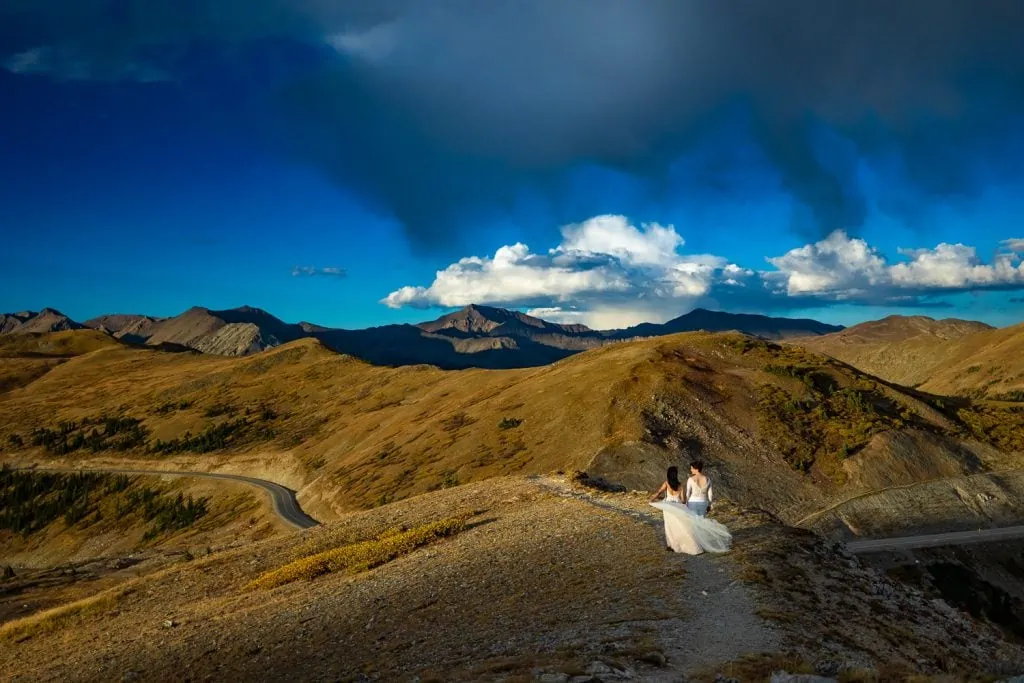 Two brides walk into the mountains of Colorado at their lesbian elopement.