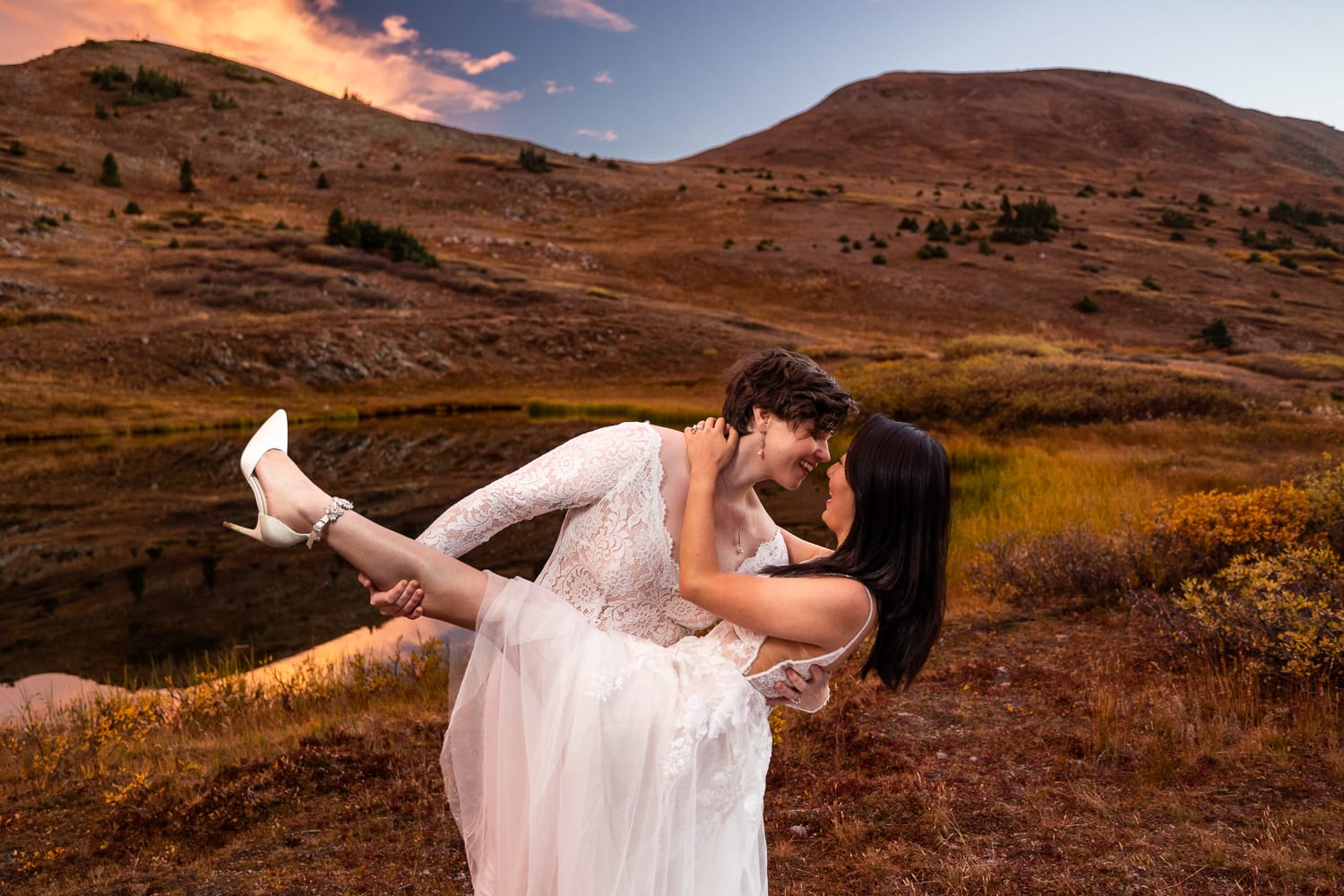 Two brides wearing white in the mountains of colorado at their elopement at sunset.