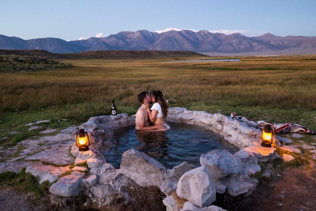 An elopement couple shares a steamy kiss in a natural hot spring.