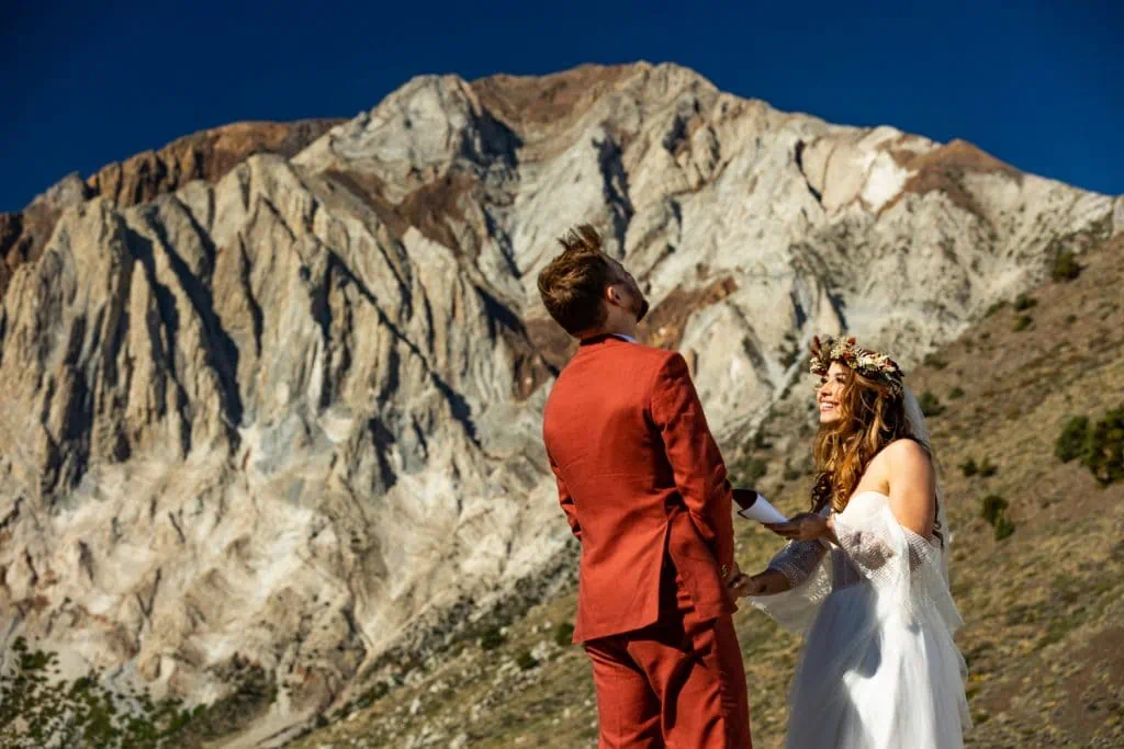 A bride and groom laugh at their destination elopement ceremony in the mountains.