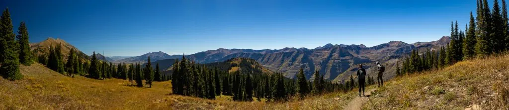 A panoramic view of two hikers enjoying views of mt crested butte in September.