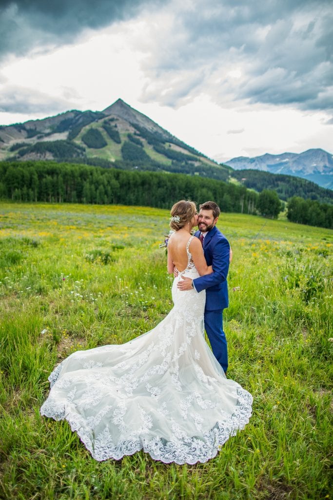 An elopement couple embrace in front of the mountain peak of Crested Butte.