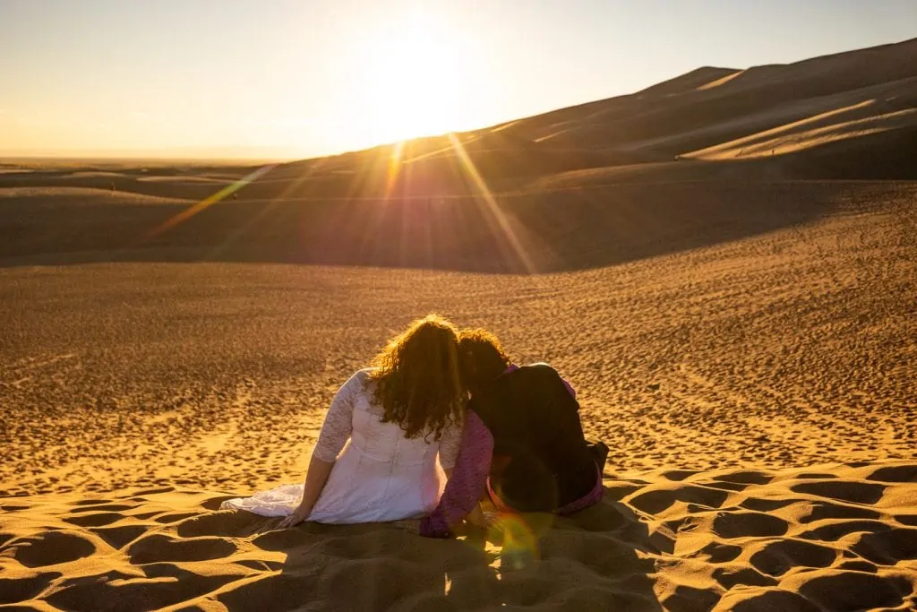 A wedding couple watches the sun set from Great Sand Dunes national park. 