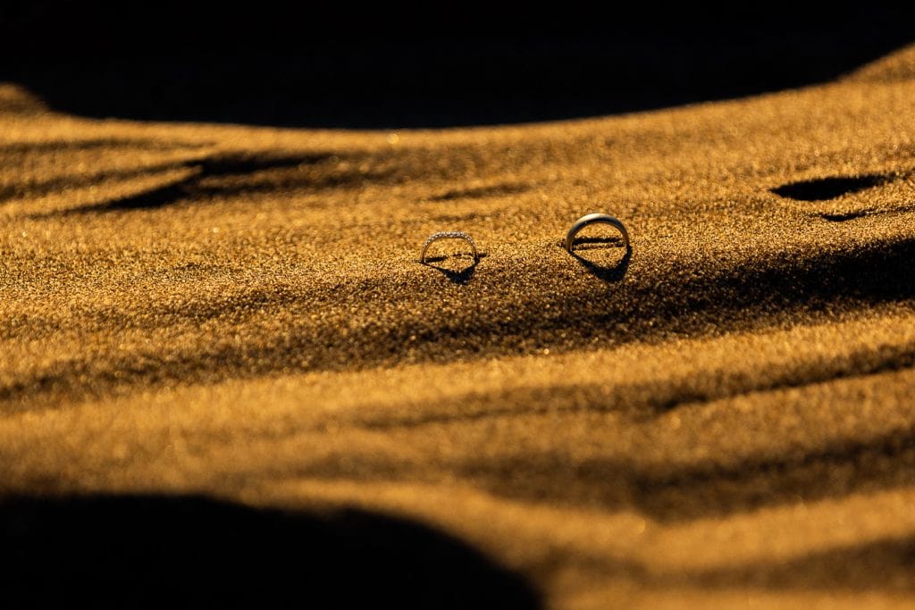 Wedding rings in the sand dunes at sunset.