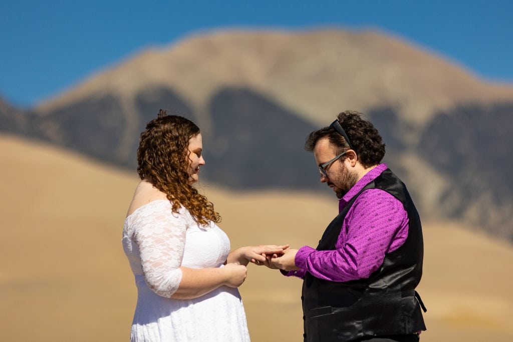 A couple exchanges rings at their elopement at Great Sand Dunes National Park in Coloraod.