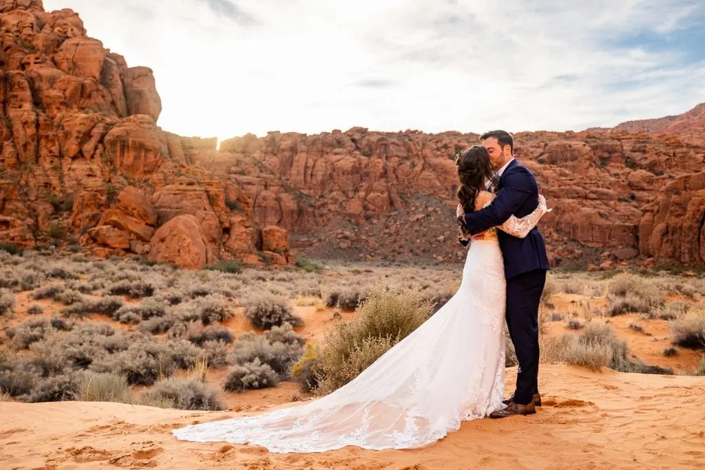 A first kiss at a desert elopement ceremony in Snow Canyon State Park in southwest Utah at sunset.