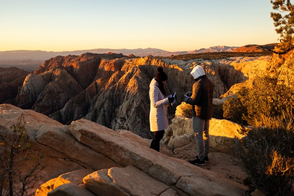 A couple reads vows at snow canyon overlook in Utah at sunrise.