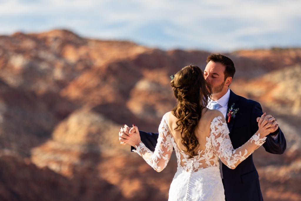 The groom hugs the bride at their snow canyon elopement.