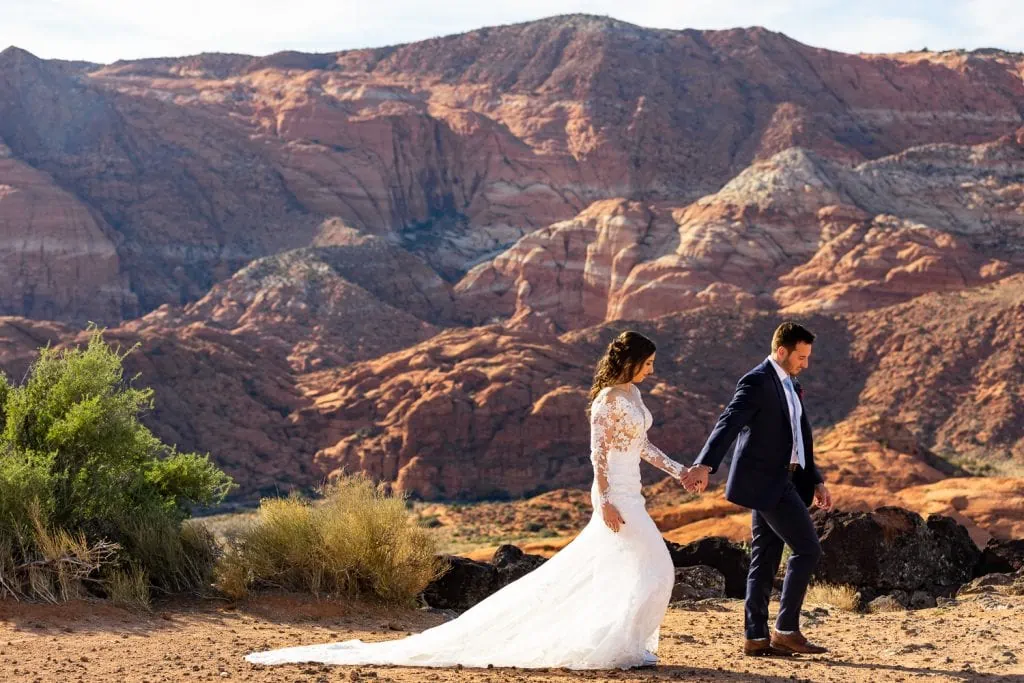 A groom leads the bride along the edge of Snow Canyon in their elopement photos.
