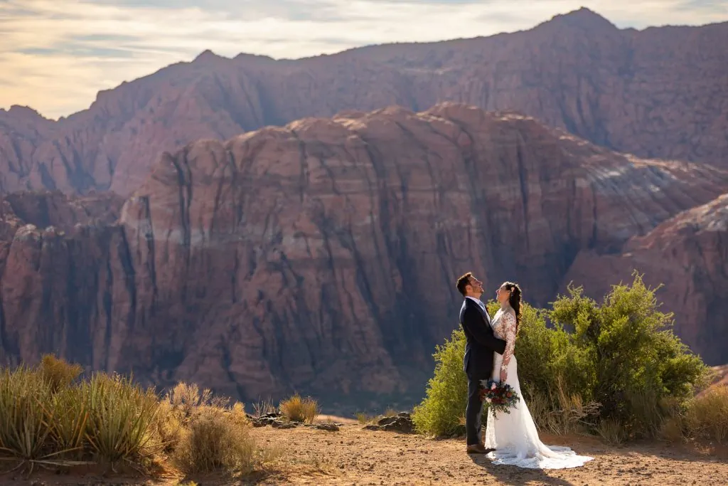 A wedding couple laughs on the edge of Snow Canyon state park in Utah.