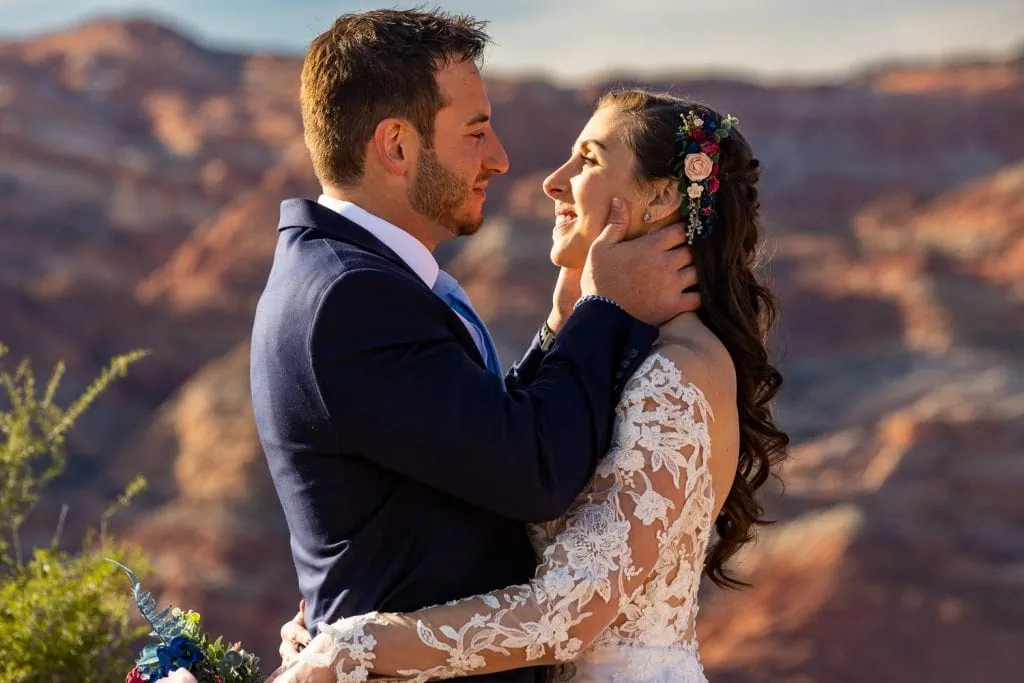 A groom tenderly holds his wife's face at sunset in the desert for their Arizona elopement.