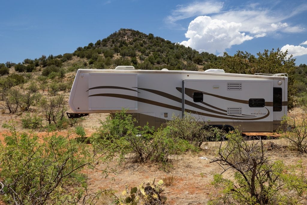A large 5th wheel white camper is shown in a scrub landscape in Arizona. This nomadic home on wheels allows the photographer to travel across the entire southwestern united states.