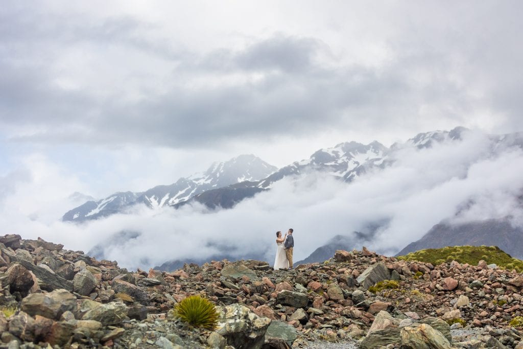 Foggy mountains surround the adventure elopement couple in Hooker Valley, New Zealand. 