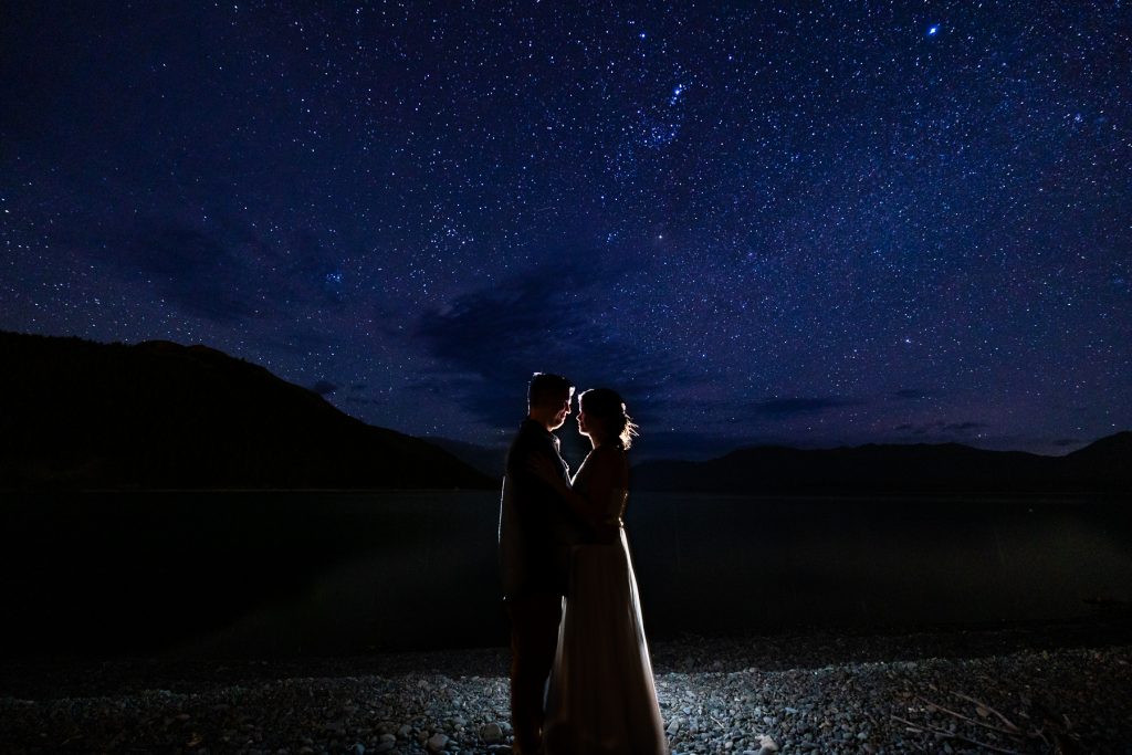 A silhouette of the elopement couple after their adventure in the mountains of New Zealand at night with a starry sky. 