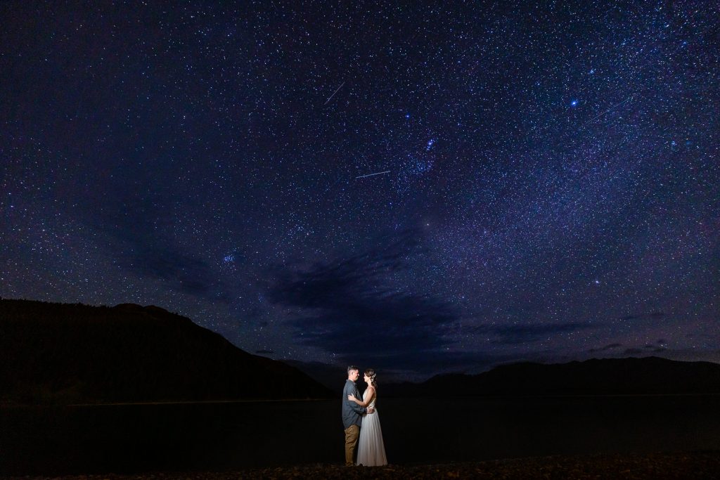 An elopement under the stars at Lake Tekapo by astrophotographer Lucy Schultz. The purple and blue sky is filled with stars.