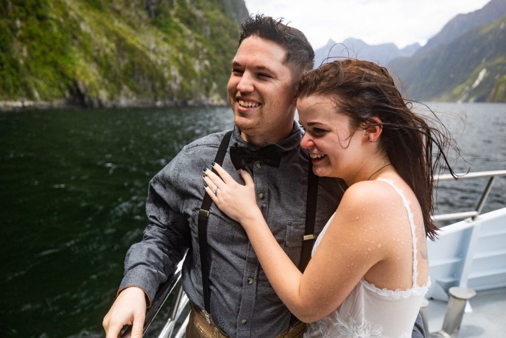 The elopement couple is soaking wet after feeling the spray of Stirling Falls waterfall in Milford Sound, New Zealand.