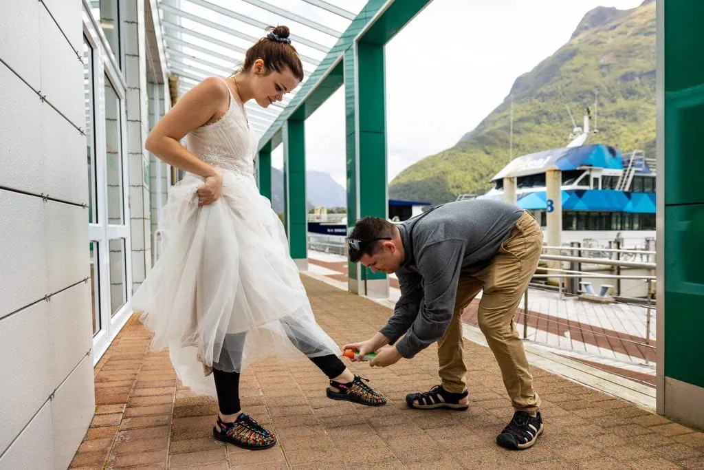 The groom applies bugspray to his bride's feet in New Zealand. 