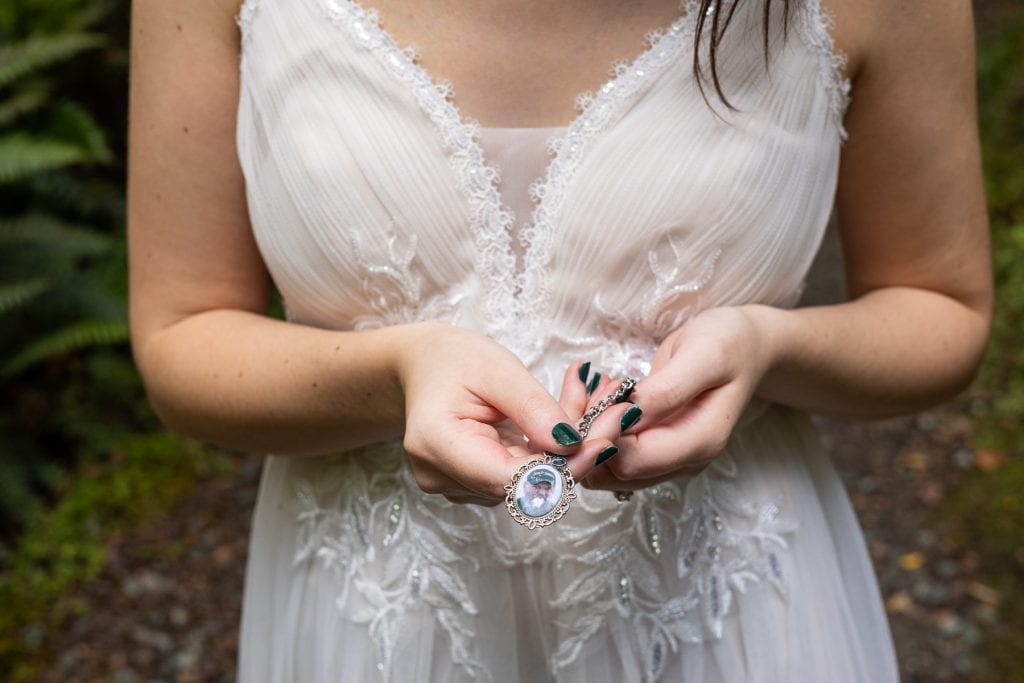 The bride holds a locket with her father's photo on it.