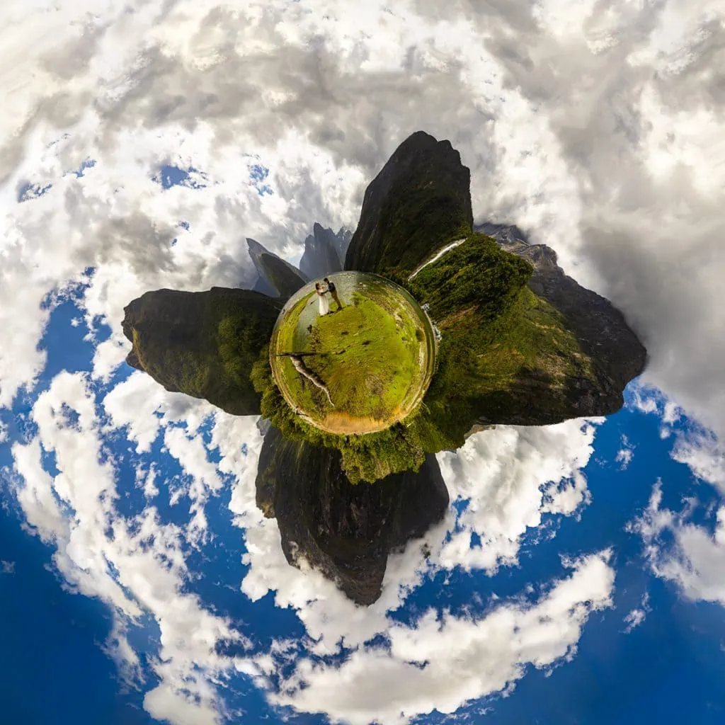 A tiny planet image showing the panoramic view of Milford Sound. The elopement couple is in wedding clothes in the center.
