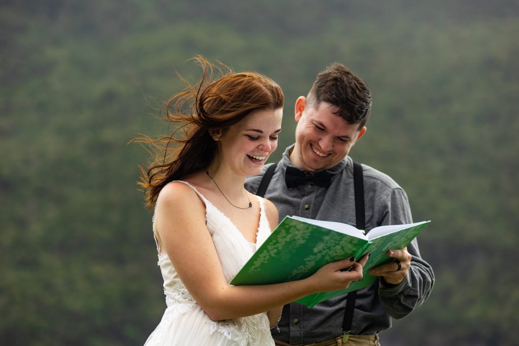 The elopement couple laughs together of a book with messages from their family and friends. 