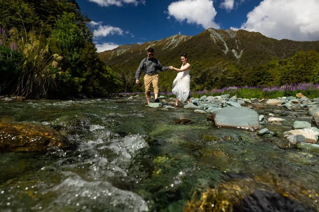 The elopement couple daringly crosses an icy river in New Zealand.