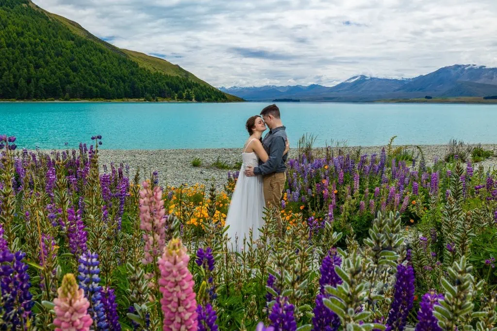 A new zealand adventure elopement at Lake Tekapo, south Island, with turquoise water and colorful flowers.