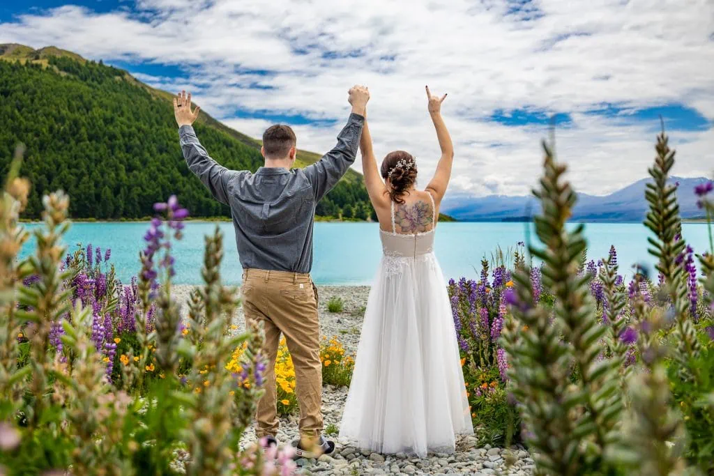 The elopement couple triumphantly puts their arms in the air after their wedding in New Zealand.