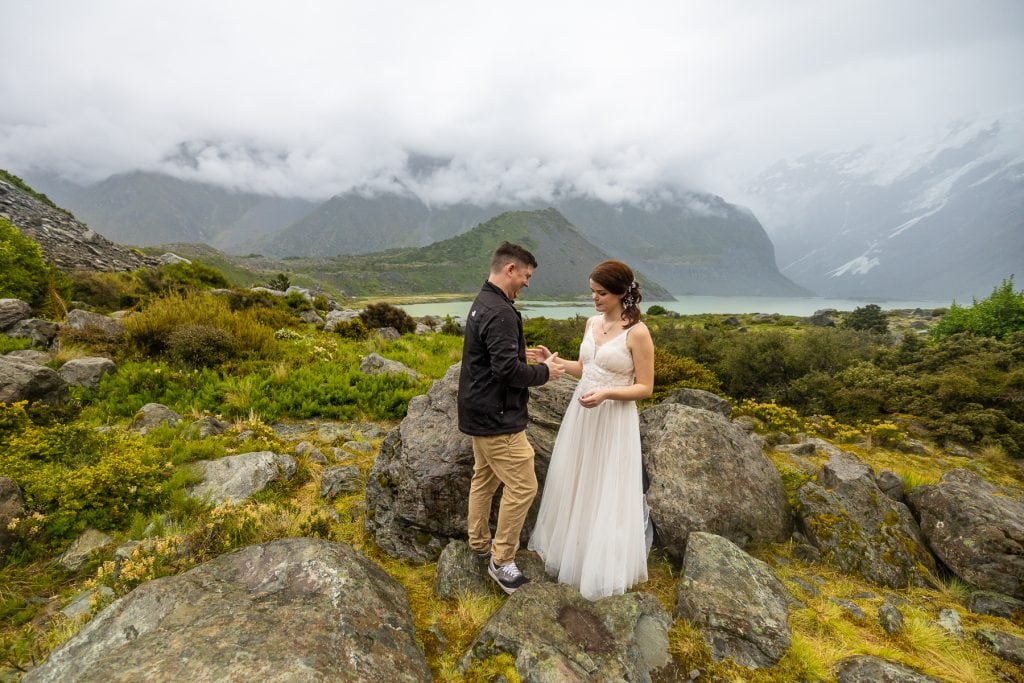 The wedding couple creates a secret handshake while hiking in the foggy mountains of New Zealand.