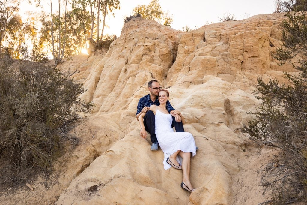 A unique elopement couple with alternative style relaxing on a desert formation at their California Elopement.