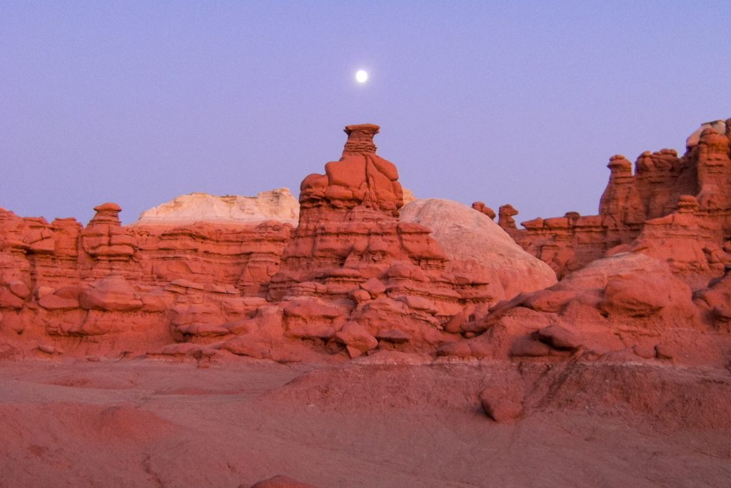 The moon rises over an orange hoodoo at Goblin Valley State Park in central utah.