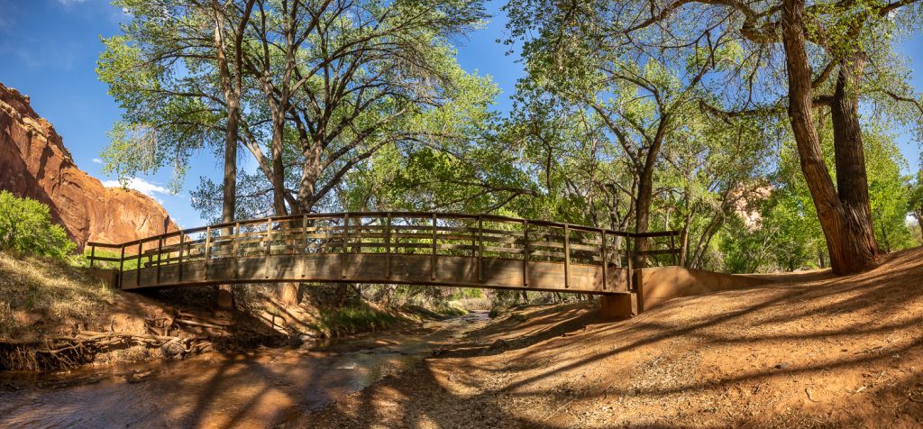 A historic bridge across the river that runs through the green central park of Capitol Reef National Park.