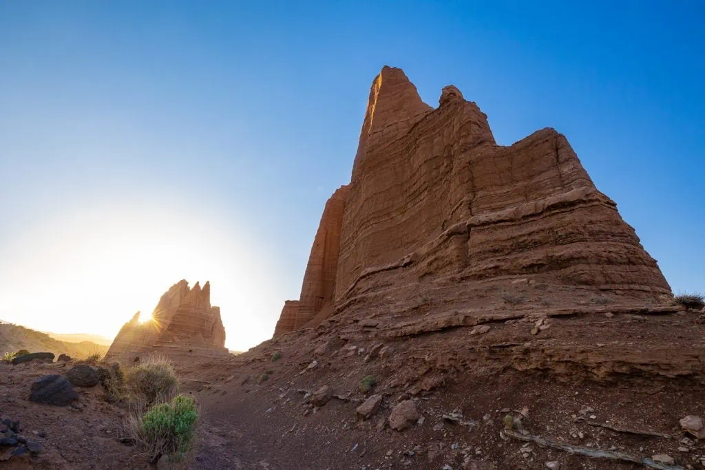 The Cathedral Valley in northern Capitol Reef National Park features enormous stone fins. The sun is setting behind them.