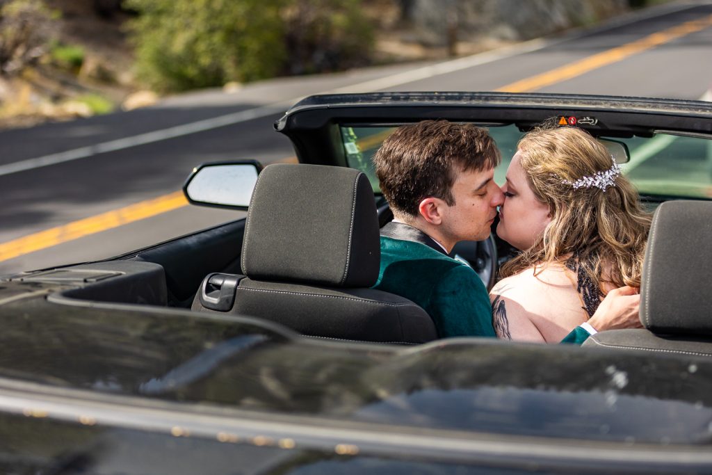 A just married elopement couple kisses in the front seat of their black convertible in yosemite national park.