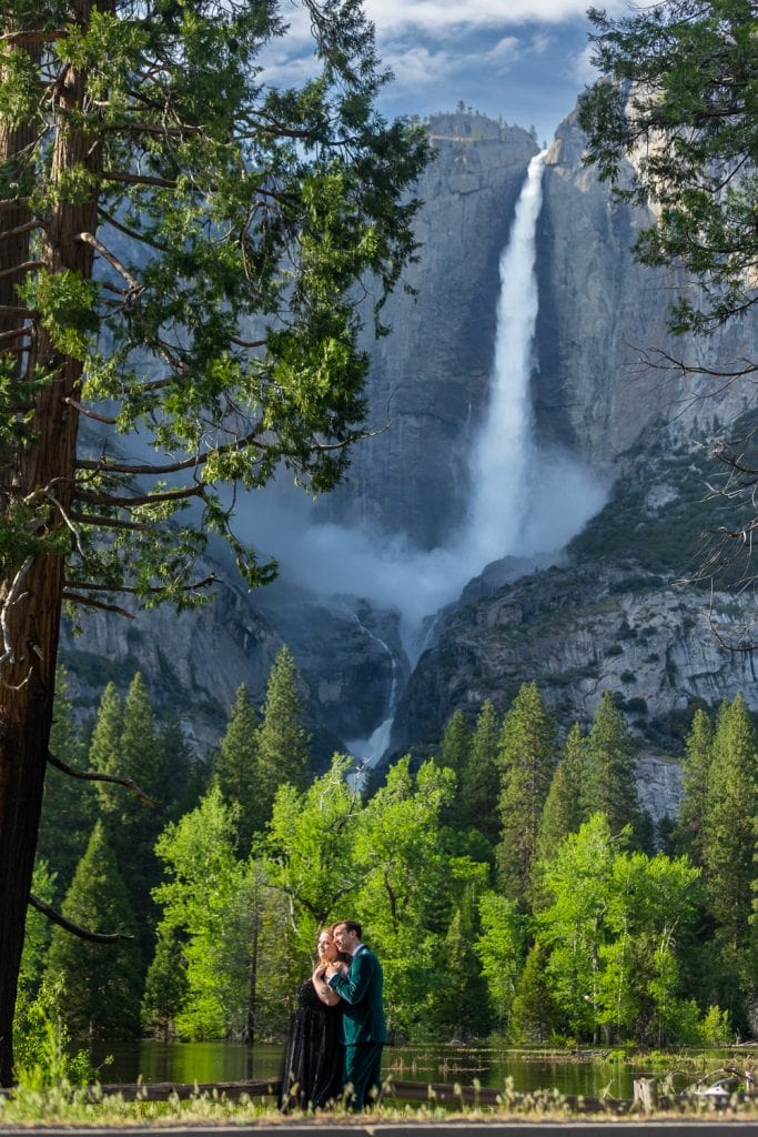 The elopement couple in Yosemite is dwarfed by the tallest waterfall on the continent behind them.