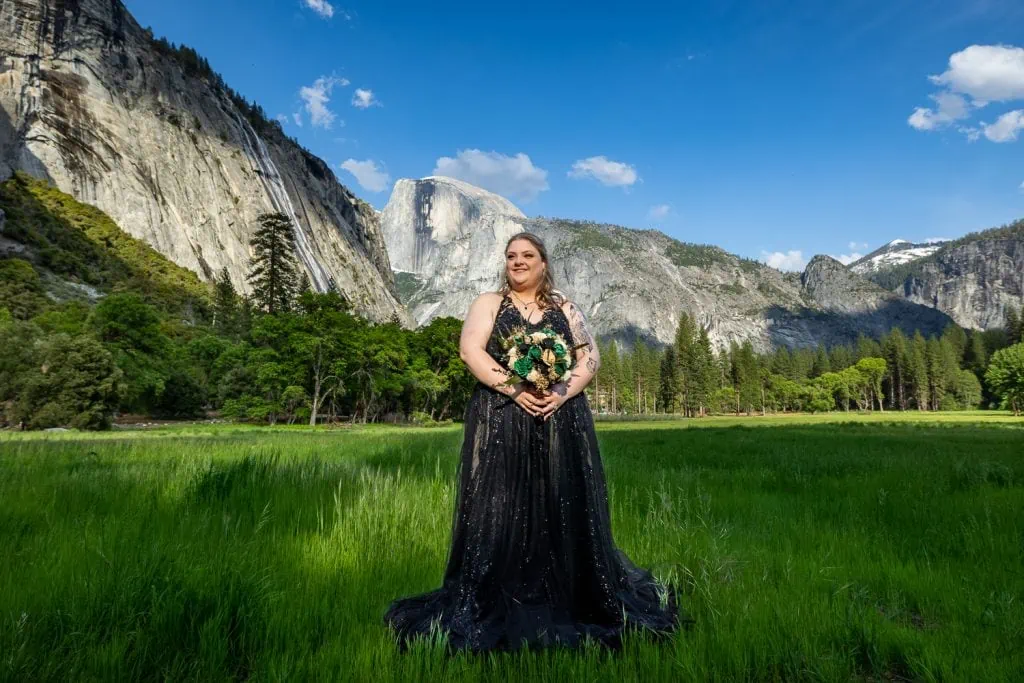 A beautiful plus sized bride stands in front of Half Dome in Yosemite National Park wearing a black sparkling wedding dress.