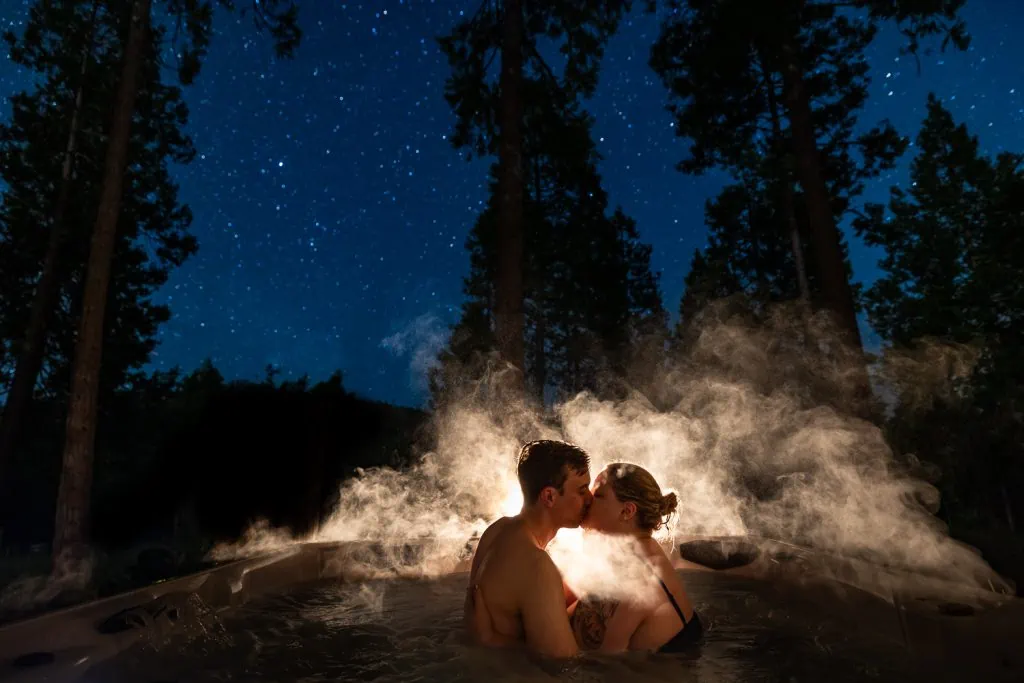 A dramatic photo of a yosemite elopement couple sharing a steamy kiss in the hot tub under the stars.