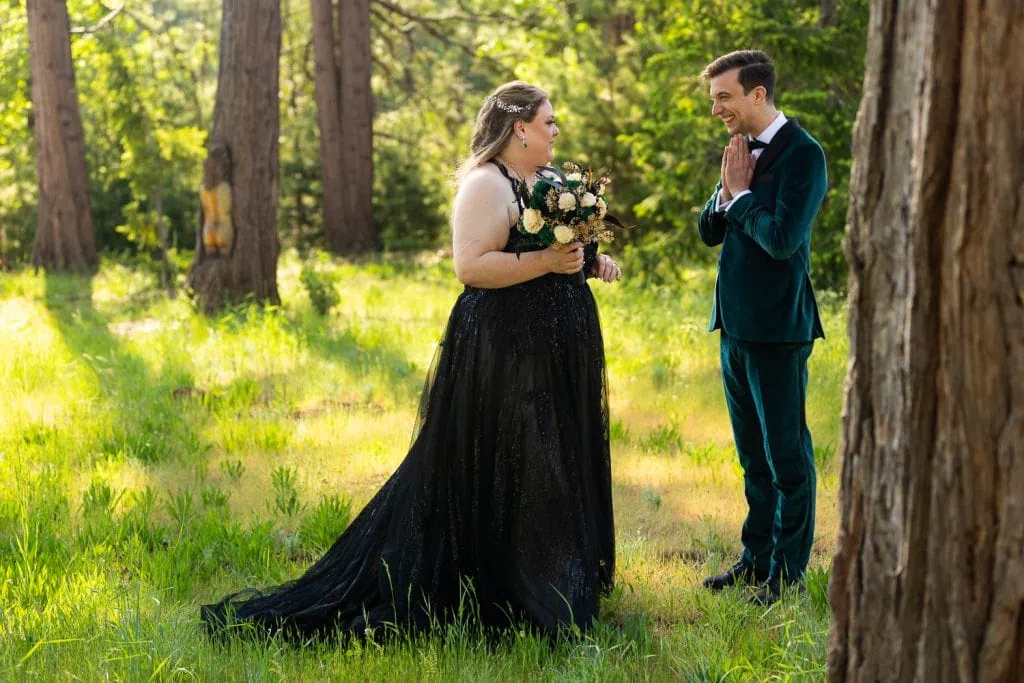 The excited bride and groom stand in a forest having a first look before their Yosemite elopement photos.