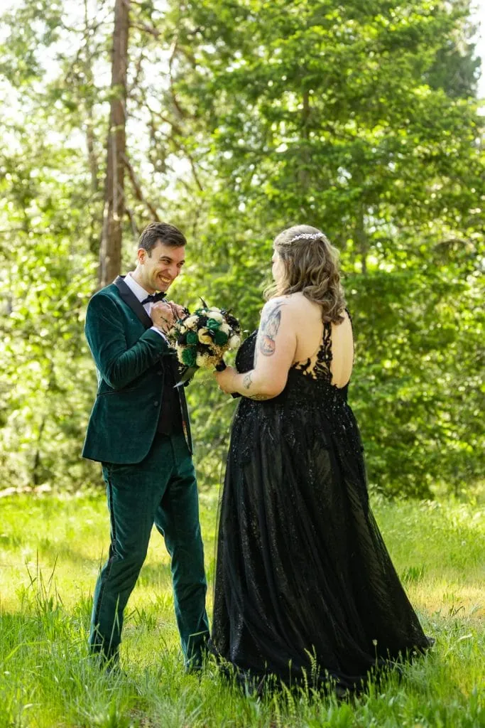 The groom clasps his hands in excitement at seeing his bride dressed in an untraditional black dress.