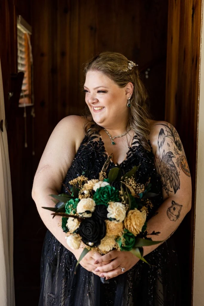 A yosemite elopement bride giggles in her black sparkly dress and green and black flowers.