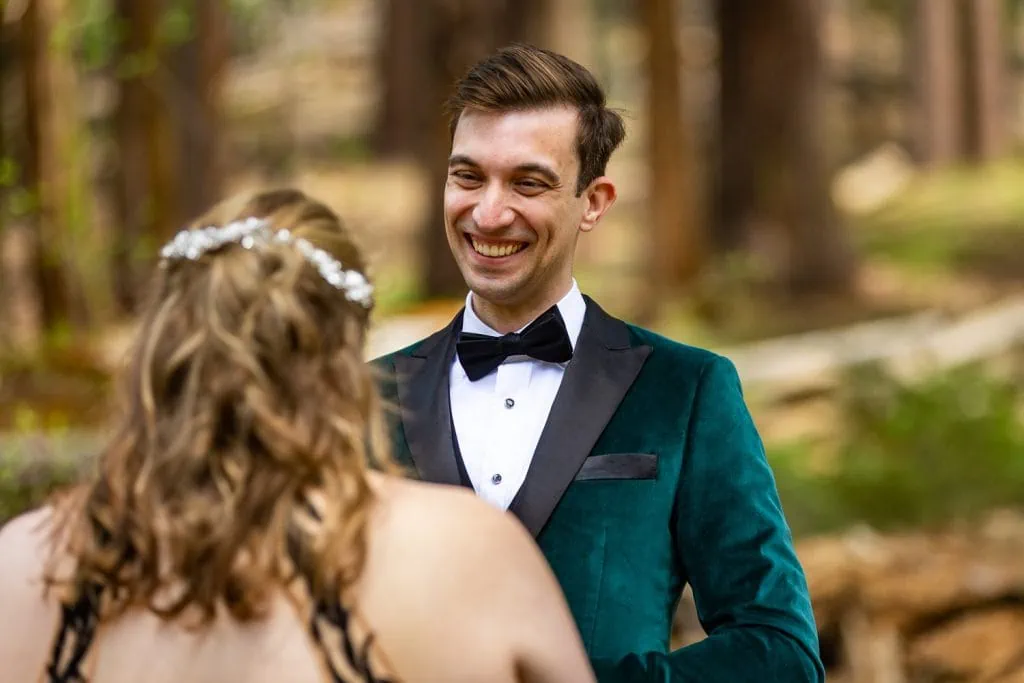 The groom smiles over the brides shoulder as he hears her read her elopement vows in this candid photo in yosemite.
