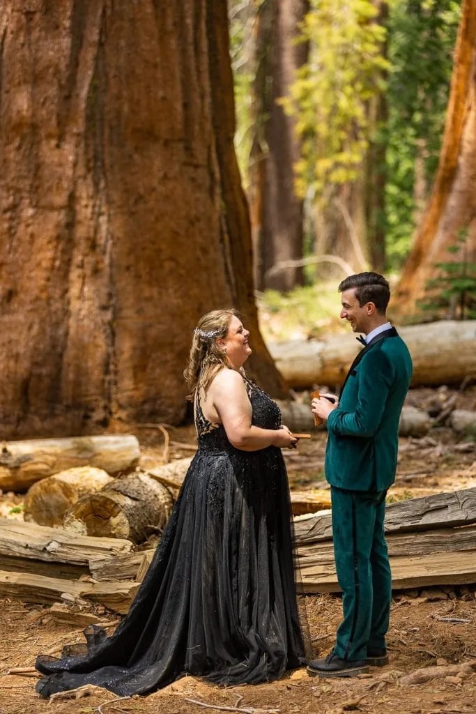 A colorful photo of a bride in a black dress and a groom in a green tuxedo laughing during their intimate yosemite elopement photos.