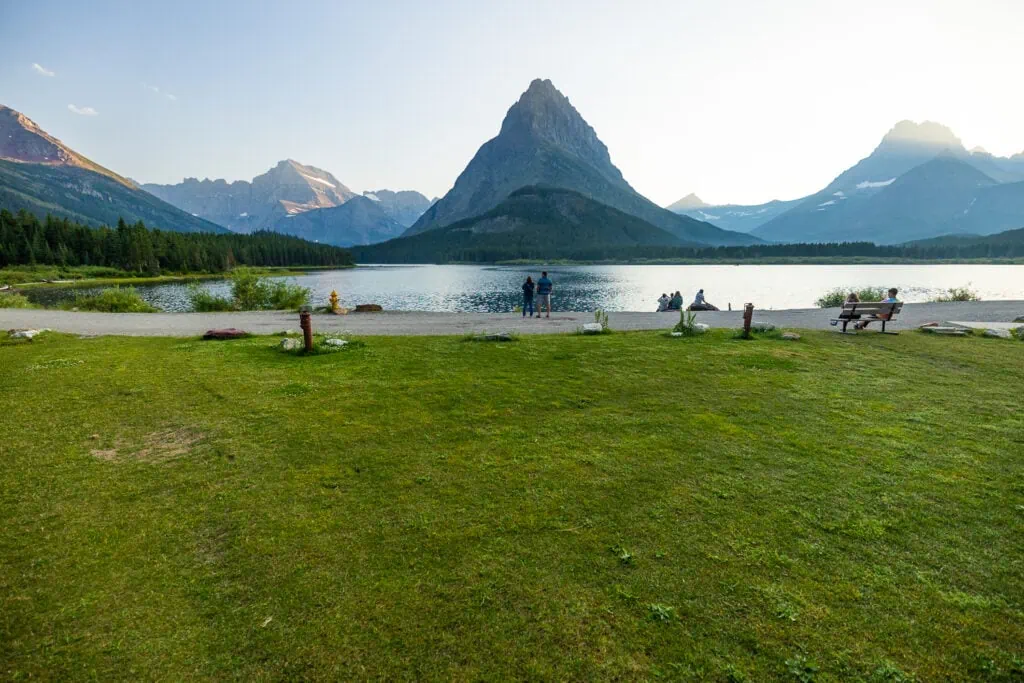 A green lawn sprawls out before the shore of Swiftcurrent Lake in Many Glacier. This is one of the elopement ceremony sites in Glacier National Park.