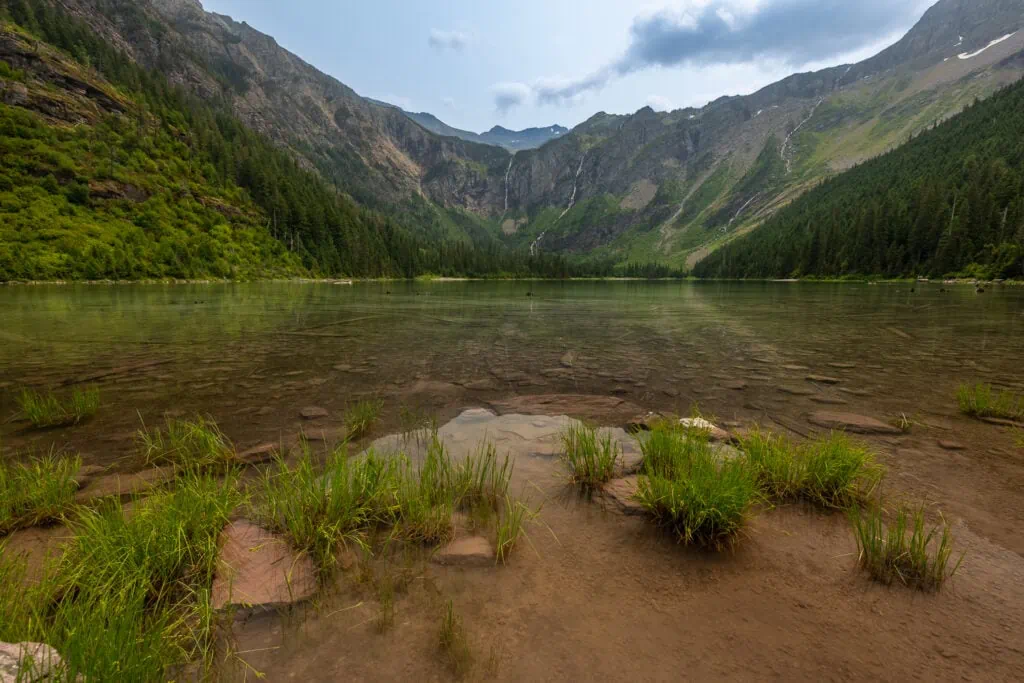Avalanche lake is surrounded by cliffs and many waterfalls in this landscape photo by Glacier National Park photographer Lucy Schultz.