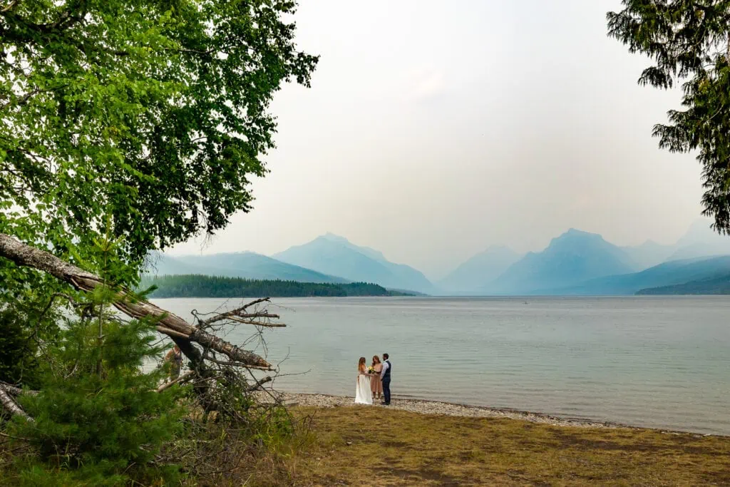 An elopement ceremony at Ryans Beach in Glacier National Park with wildfire haze.